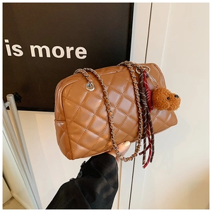 Detail of brown quilted chain shoulder bag featuring a cute plush bear charm accessory