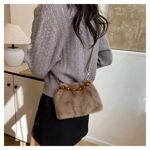 Détail du sac seau en fausse fourrure avec poignée en perles et sangle amovible
