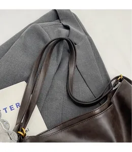 Detail of vintage dark brown leather bag showing golden metal rings and long strap