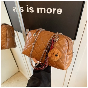 Close-up of brown quilted pillow bag with silver chain strap and poodle charm
