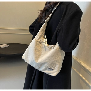 Detail der cremeweißen Nylon-Tote-Bag mit Texturfalten und Logo für das Büro