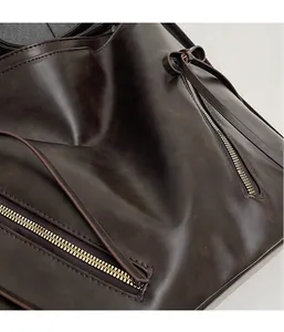 Close-up of vintage dark brown tote bag showing textured PU leather and metal zipper details