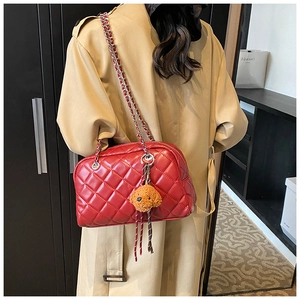 Detail of red quilted pillow bag with chain strap and teddy plush charm on trench coat