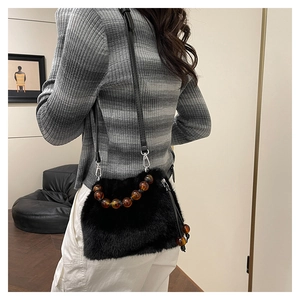 Détail du sac seau en fausse fourrure noire avec poignée en perles d'ambre et bandoulière