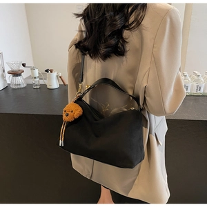 Rear view of a model carrying a large black canvas tote bag with a cute puppy pendant