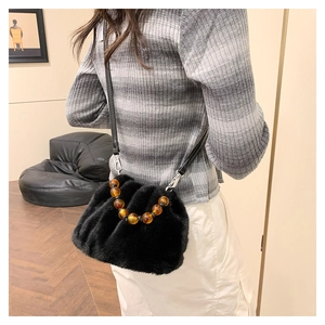Détail du sac bandoulière en fausse fourrure noire avec perles ambre et boucles en métal
