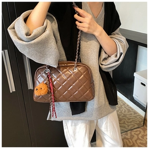 Detailed view of brown quilted pillow bag with silver chain strap and plush charm