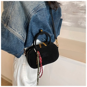 Détail du sac à main noir en daim mat avec lettres gaufrées et charm en cordelette