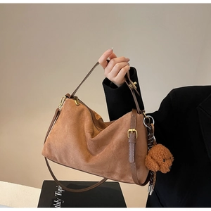 Detailed shot of brown suede hobo bag with gold hardware and plush teddy charm