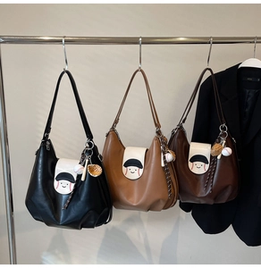 Detailed view of three hobo shoulder bags with baseball charms on metal hangers
