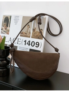 Brown contrast leather crescent bag with unique large knot handle on fashion magazine
