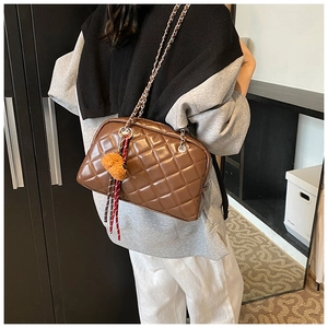 Detailed view of brown quilted leather pillow bag with silver chain and plush pendant