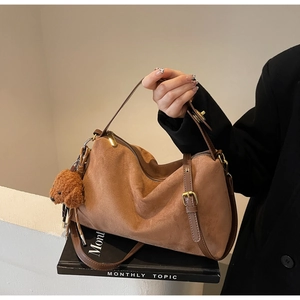 Detail of a brown suede pleated shoulder bag with a cute plush dog charm accessory