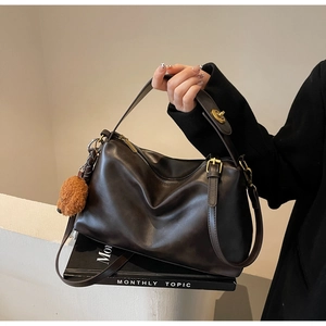 Detail of vintage brown leather tote bag with adjustable strap and cute plush bear charm