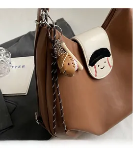 Close-up of brown leather tote featuring baseball-style embroidery and creative charms