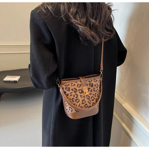 Modella indossa borsa a secchiello leopardata con finiture in pelle marrone e chiusura oro