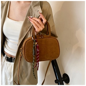 Détail du sac bowling en daim marron avec gaufrage KORSK et pendentif tissé