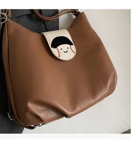 Brown soft leather Hobo bag featuring a unique cartoon baseball cap smiley face flap