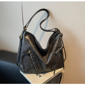 Detail of charcoal grey PU leather tote bag with dual bow tie accents and metal zipper