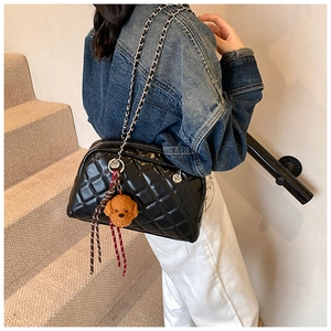 Quilted black pillow bag with chain strap and teddy charm shown on a model