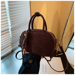 Gros plan d'un sac à main vintage en daim marron foncé avec gaufrage et porte-clés décoratif