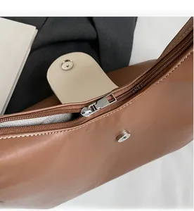 Detail of smooth silver zipper and stitching on caramel leather shoulder bag with liner