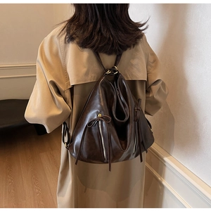 Detail view of dark brown leather backpack with vertical zippers and tassel accents