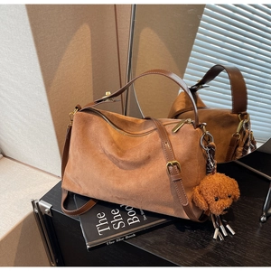 Detail of vintage brown suede tote bag with adjustable strap and cute plush puppy charm