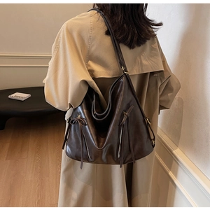 Detail of dark brown leather hobo bag with dual vertical zippers and long leather tassels