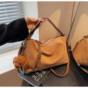 Close-up of vintage brown suede tote bag with plush dog charm and smooth leather straps