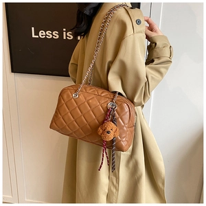 Detail of brown quilted pillow bag with silver chain strap and plush teddy bear charm