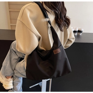 Vue détaillée du grand sac cabas noir en toile avec étiquette fashion et bandoulière