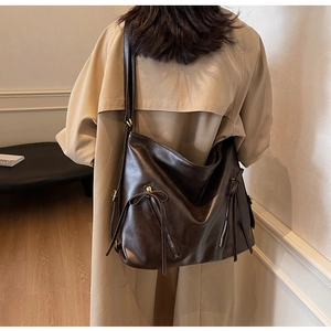 Detail view of deep brown vintage hobo bag with zipper decor and bow on model's shoulder
