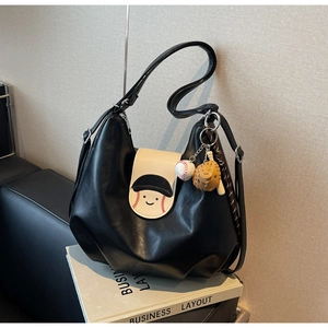 Detail of black hobo bag with cartoon baseball face flap and creative leather charms