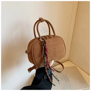 Vue détaillée du sac en cuir dépoli marron avec breloque tissée et logo embossé