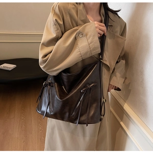 Detail of dark brown vintage tote bag with side zippers and leather tassels on model