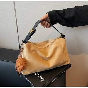 Detail of camel suede hobo bag featuring black leather strap and brown teddy bear charm