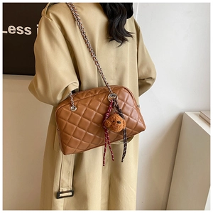 Detail of brown quilted pillow bag with silver chain strap and plush bear charm