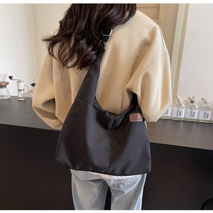 Détail d'un grand sac cabas noir en toile montrant l'étiquette mode et la bandoulière