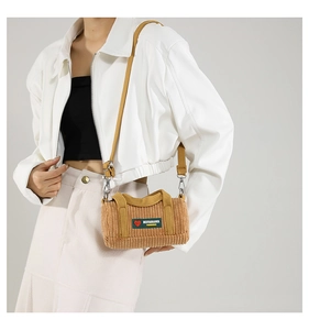 Close-up of brown corduroy cylinder bag with embroidered logo and adjustable strap