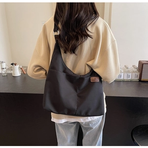 Détail du grand sac cabas noir en toile avec bandoulière réglable et logo de mode