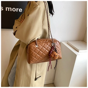 Close-up of brown quilted pillow bag with chain strap and cute bear keychain charm
