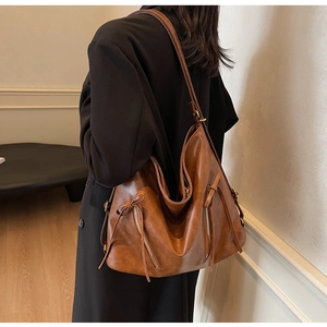 Close-up of a vintage brown leather hobo bag showing texture and side zipper detail