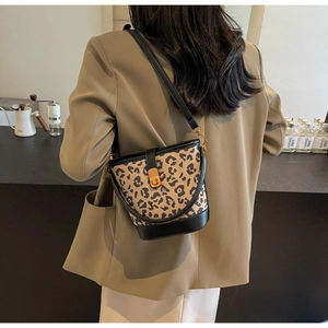 Dettaglio della borsa a secchiello leopardata con finiture in pelle nera e chiusura oro
