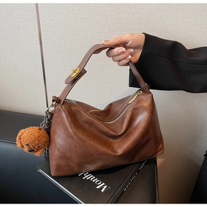 Close-up of a vintage brown leather hobo bag with gold zipper and a cute dog pendant