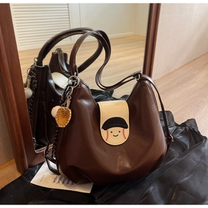 Close-up of brown PU leather hobo bag with cartoon baseball flap and charm