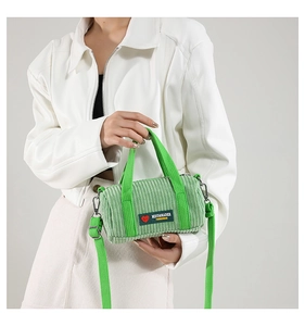 Dettaglio della borsa a cilindro in velluto a coste verde erba con logo applicato