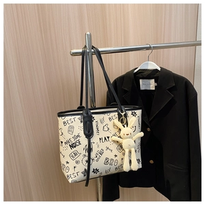 Detail of white graffiti tote bag with black lettering and plush bunny charm