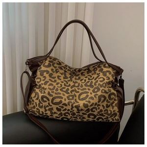 Close-up of leopard print tote bag with brown leather handles on a black seat