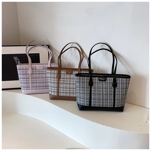 Detailed close-up of large tote bags in pink, brown and black plaid with leather handles